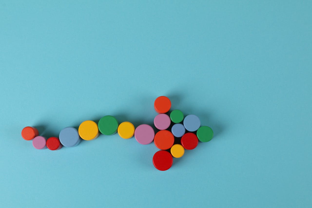 services-02 A vibrant arrow composed of colorful cylinders against a minimalist blue backdrop.